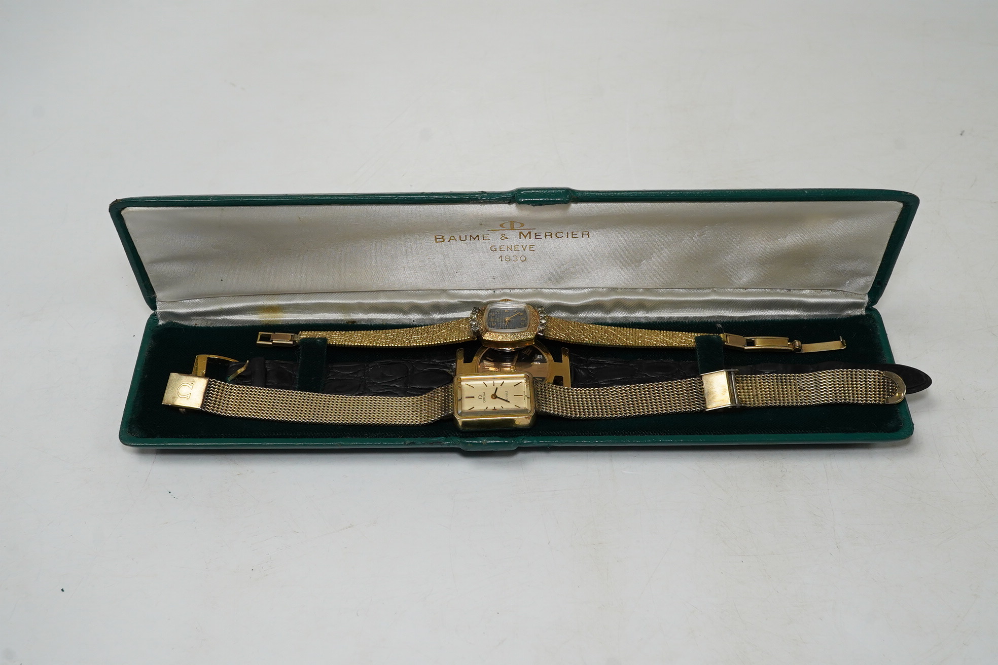 A ladies stylish Baume Mercier 18ct gold wrist watch, in original green leather case, and two gold plated wrist watches by Omega and Bucherer. Condition - Baume Mercier movement not going, later strap with gold plated bu